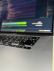 Close-up of hands typing on a laptop with cybersecurity code on screen.