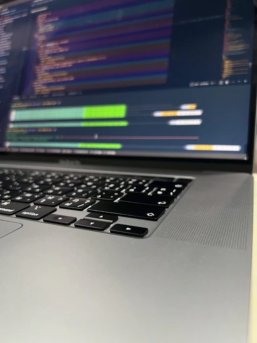 Close-up of hands typing on a laptop with code on screen.