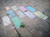 Children drawing with chalk on a sidewalk, showcasing creativity.