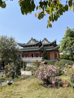 Traditional Asian temple surrounded by lush greenery and blooming flowers.