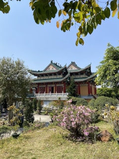 Traditional Asian temple surrounded by lush greenery and blooming flowers.