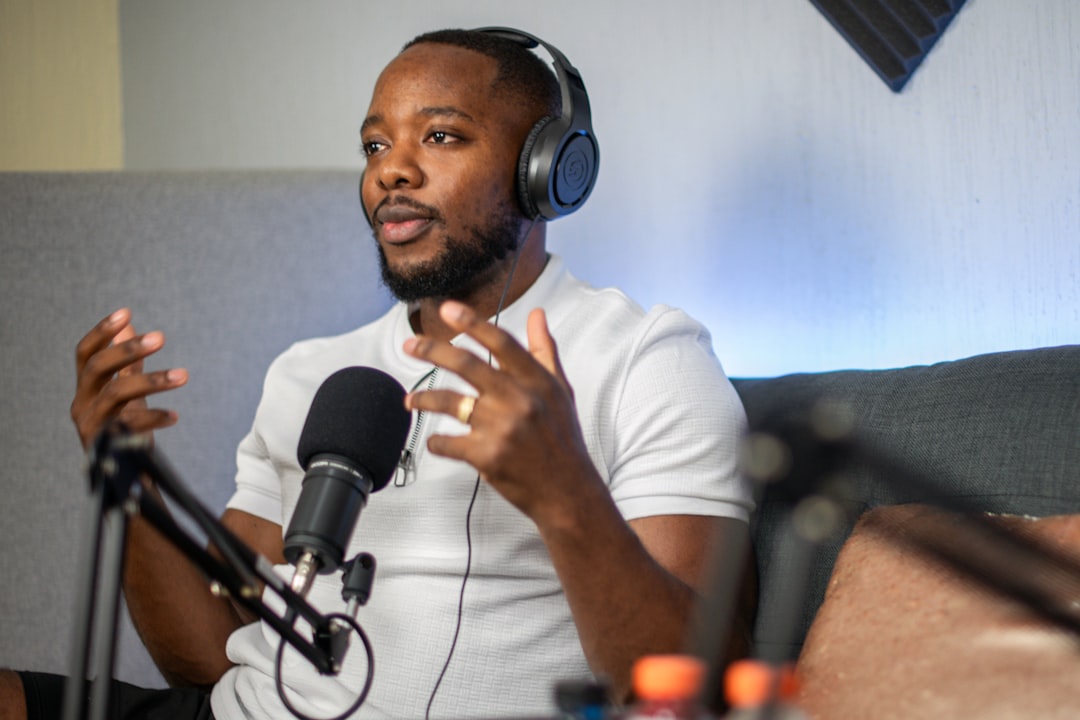a man wearing headphones sitting in front of a microphone, Podcast host, Dorian Djougoue. Follow him at: @dorian.djougoue