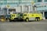Two large, lime-green airport fire trucks are parked in front of gate 52 at an airport terminal. The vehicles are equipped with fire fighting equipment and have 'R4' markings. The background includes passenger boarding bridges, airport signage and the HSBC logo on a building facade.