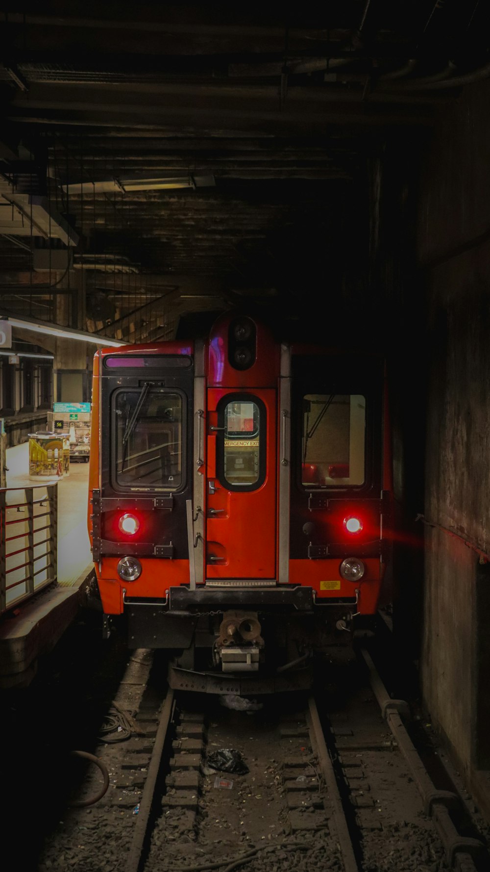 um trem vermelho viajando pelos trilhos do trem ao lado de uma plataforma de carregamento