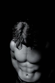 Side profile of a muscular lifter in black compression pants, mid-pump, with dramatic shadows.