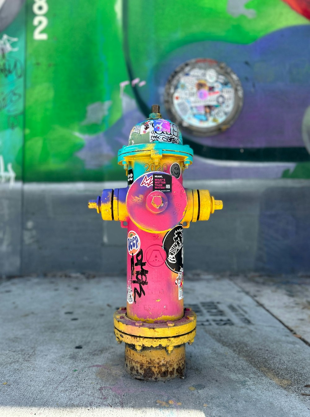 a yellow and pink fire hydrant with graffiti on it
