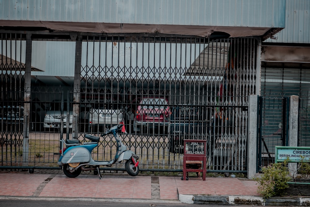 a scooter parked in front of a building behind a fence