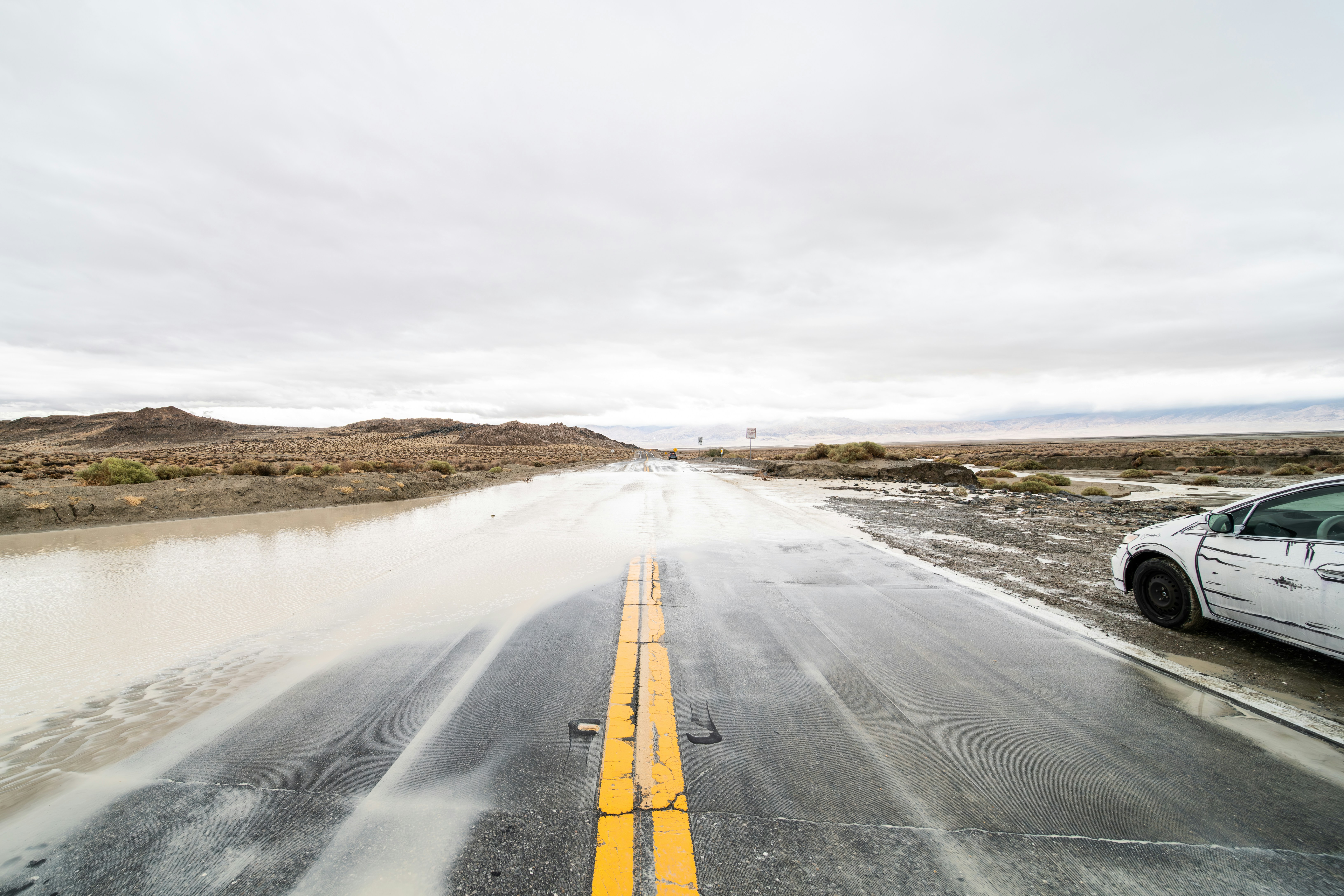 a white car driving down a wet road
