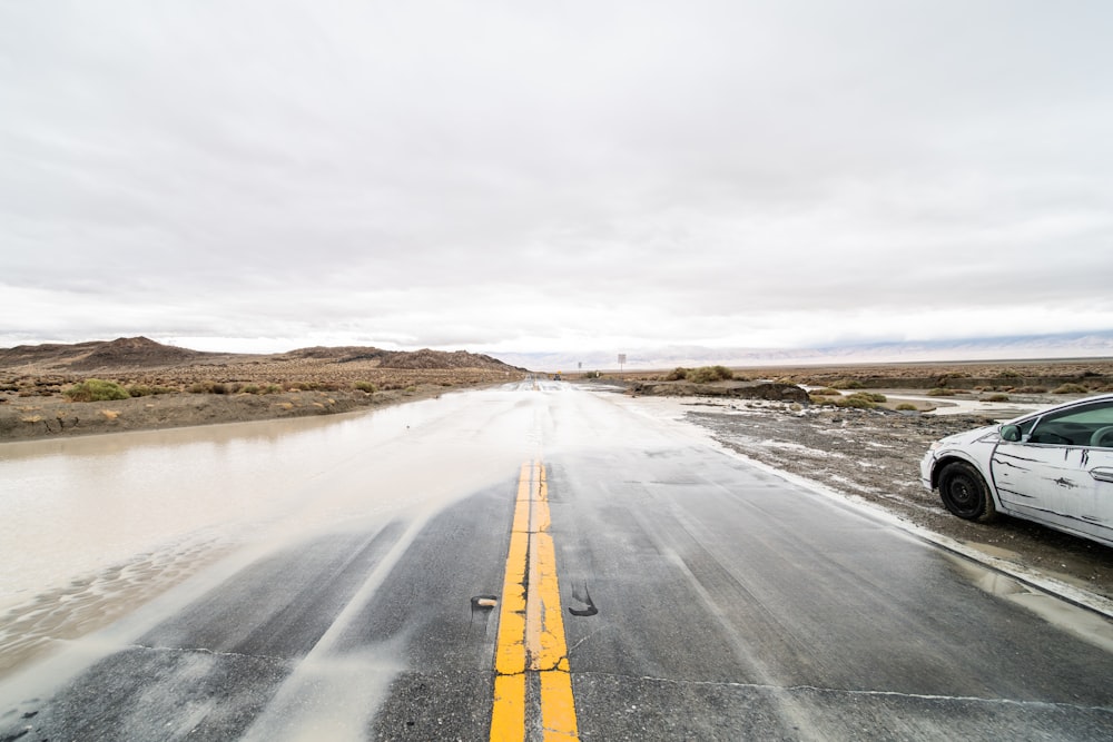 a white car driving down a wet road