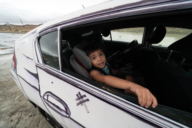A candid shot of a family road trip, packed car with luggage and kids excitedly looking out the window.