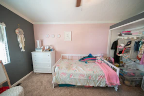A tidy, organized bedroom showcasing crisp linens and a calming pink accent wall.