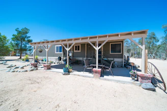 Spacious modular park home with a wrap-around porch surrounded by desert flora.