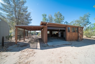 a building with a covered entrance in the middle of a dirt field