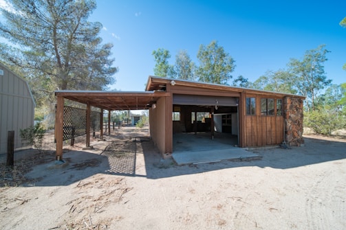 a building with a covered entrance in the middle of a dirt field