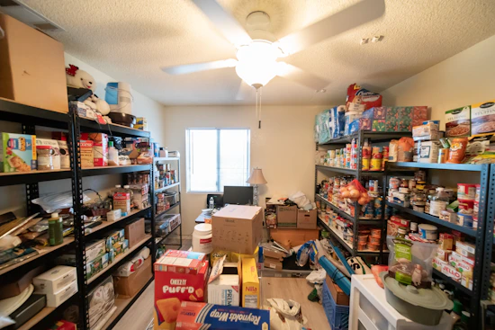 Volunteers organizing shelves stocked with nutritious food items inside the pantry.