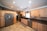 A spacious kitchen with wooden cabinetry and modern appliances, including a stainless steel refrigerator and dishwasher. The countertop is dark granite, and there is a large window above the sink allowing natural light to enter. Recessed lighting in the ceiling provides additional illumination. The flooring appears to be tile with a neutral design.