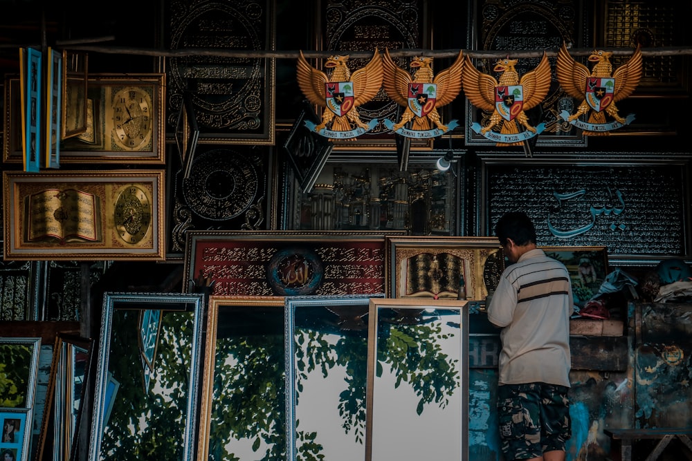 a man standing in front of a wall of framed pictures