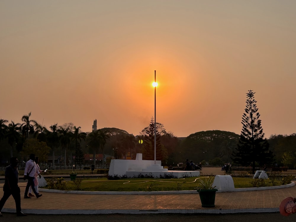 a couple of people walking around a park at sunset