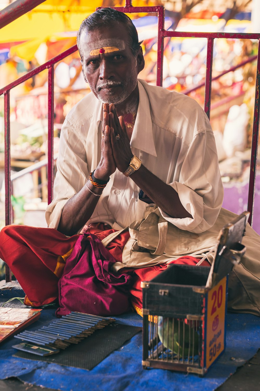 Un homme assis par terre, les mains jointes