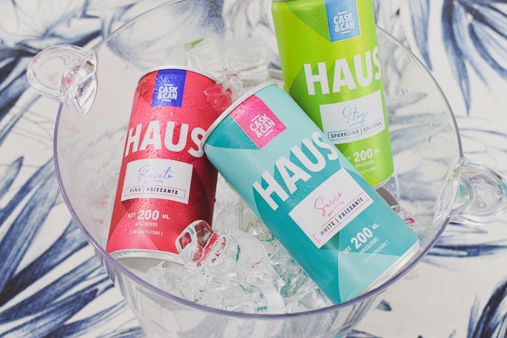 three cans of haus on ice in a glass bowl