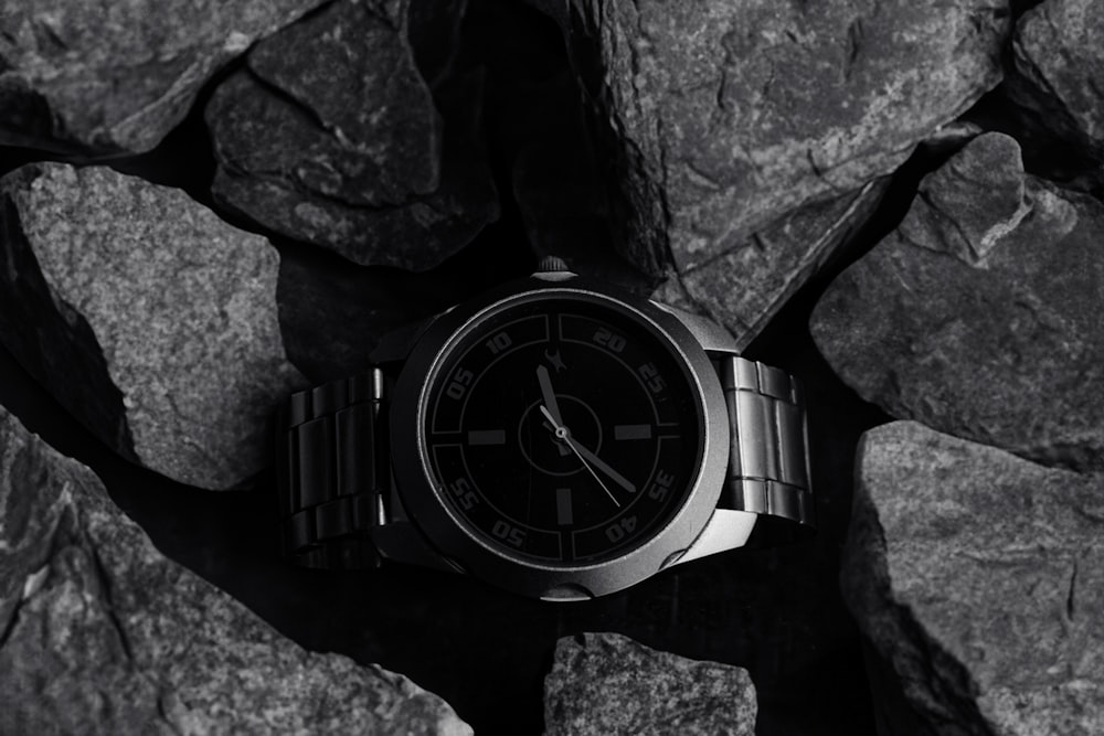a black and white photo of a watch on a rock