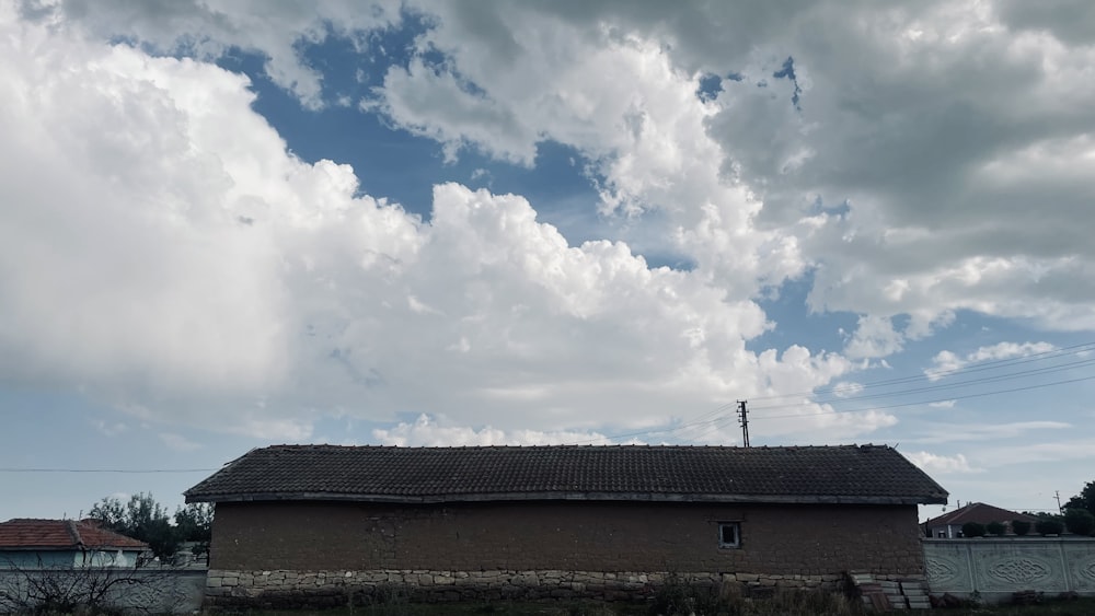 a brown building with a brown roof under a cloudy sky