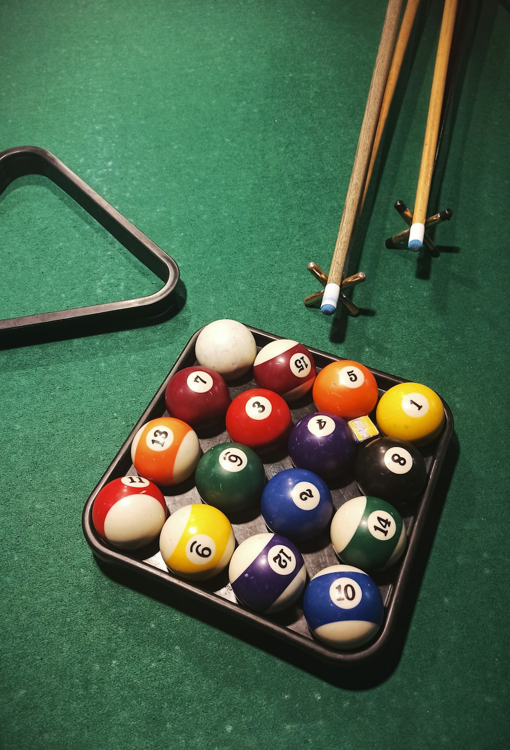 a pool table with a rack of pool balls and cues