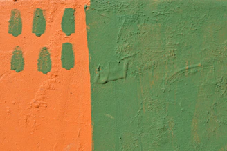 Painter applying fresh orange paint on a cozy living room wall.