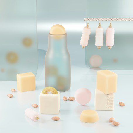 Aesthetic arrangement of pastel-colored objects on a glossy surface, featuring a frosted glass bottle with a spherical cap, cream and pale pink cylindrical objects hanging from a rope, and various bar soaps shaped as cubes with embossed text. Scattered almonds and a cut lime add visual interest.