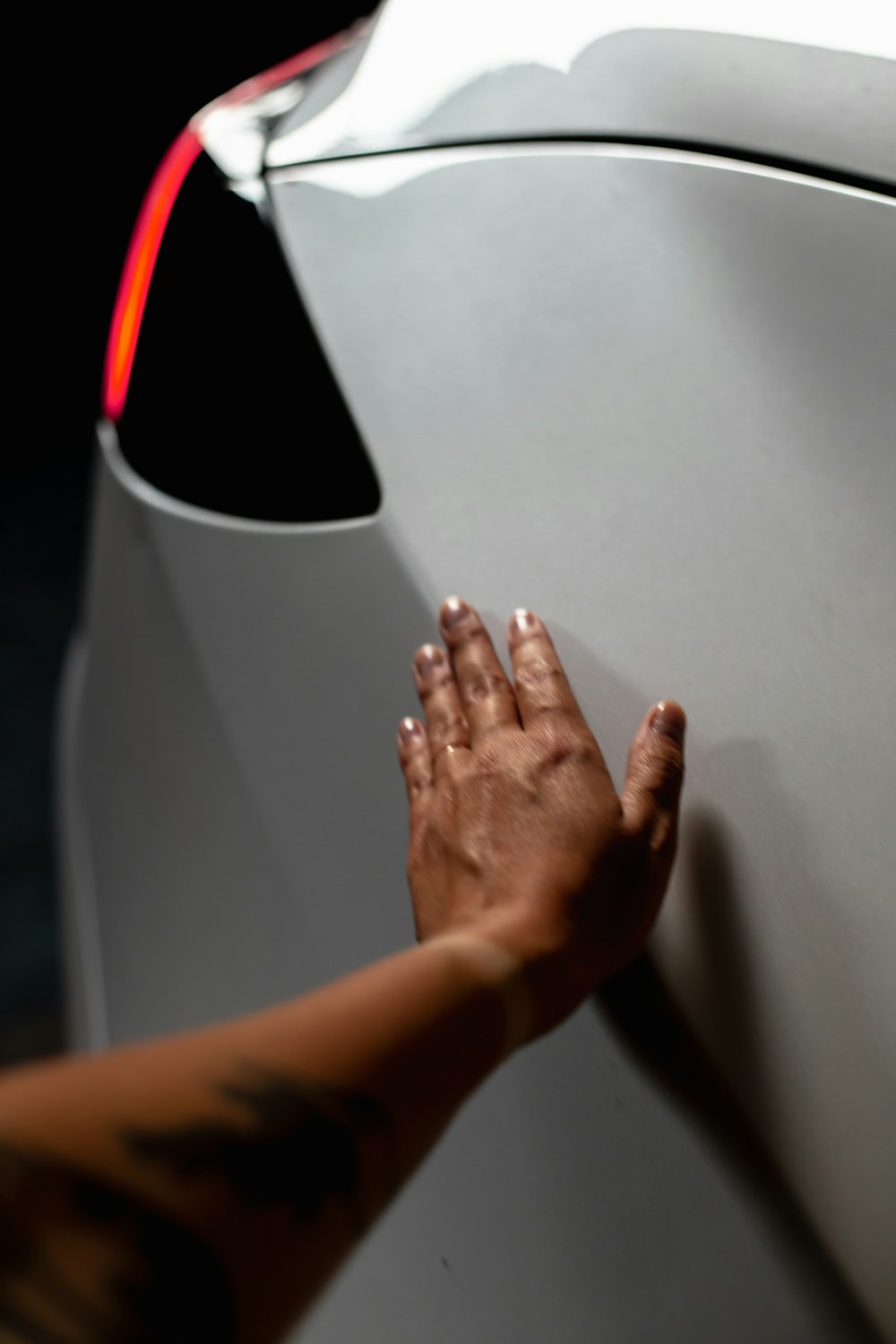 a person touching the side of a white car