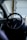 The interior of a car featuring a steering wheel with a logo in the center. A large touchscreen display is visible on the right side.