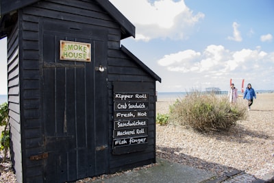 Smokers billowing savory smoke beside the restaurant near the shoreline.
