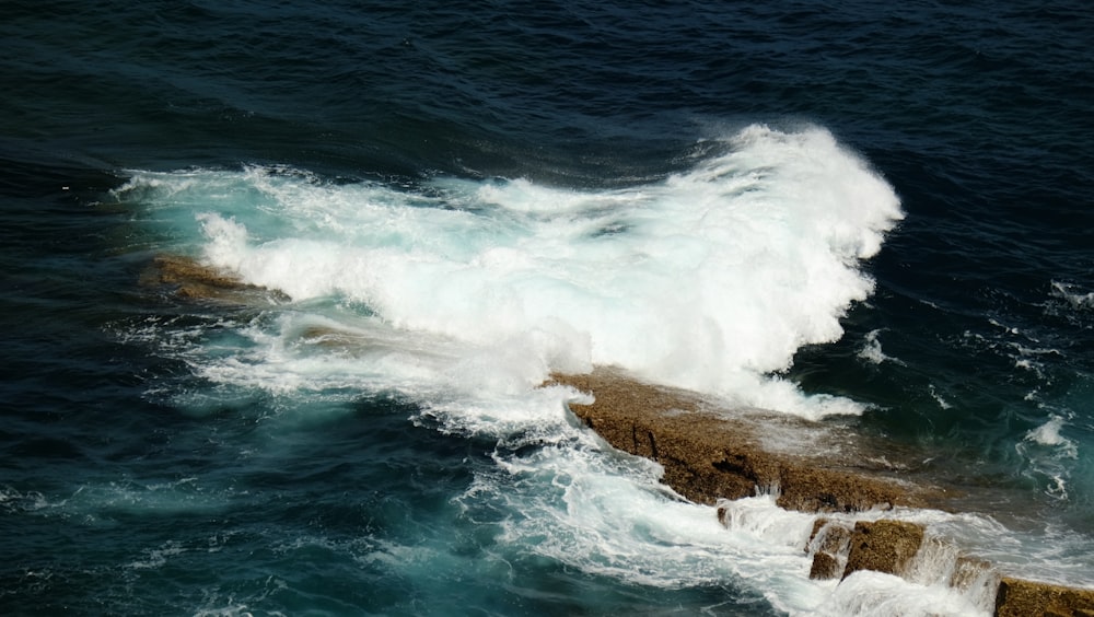 a large wave crashes into the rocks in the ocean