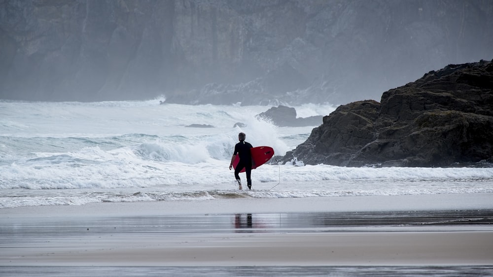 Una persona caminando en una playa con una tabla de surf