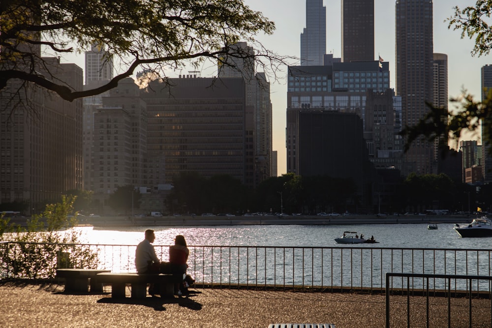 two people sitting on a bench near a body of water