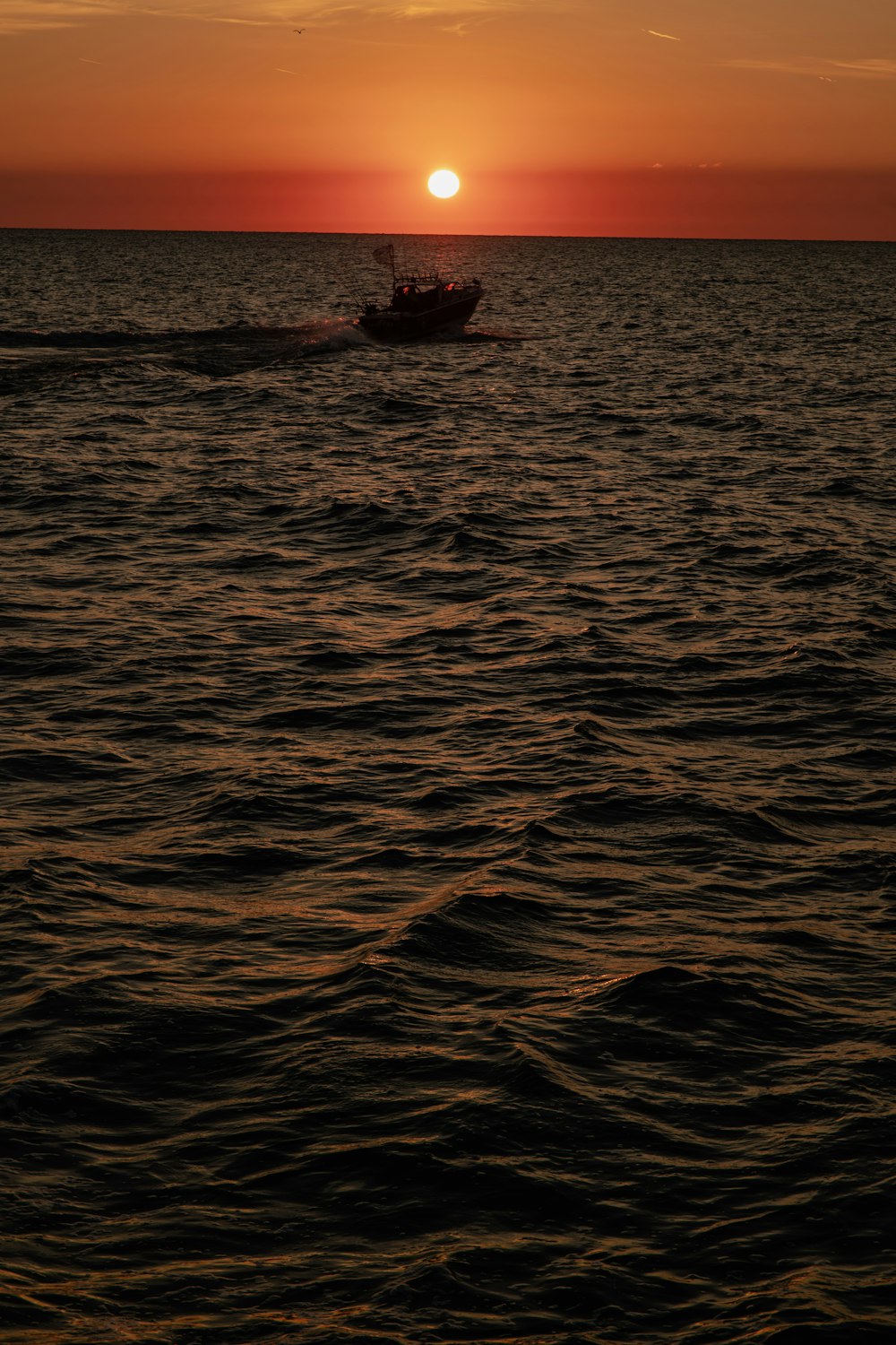 a boat in the ocean with the sun setting in the background