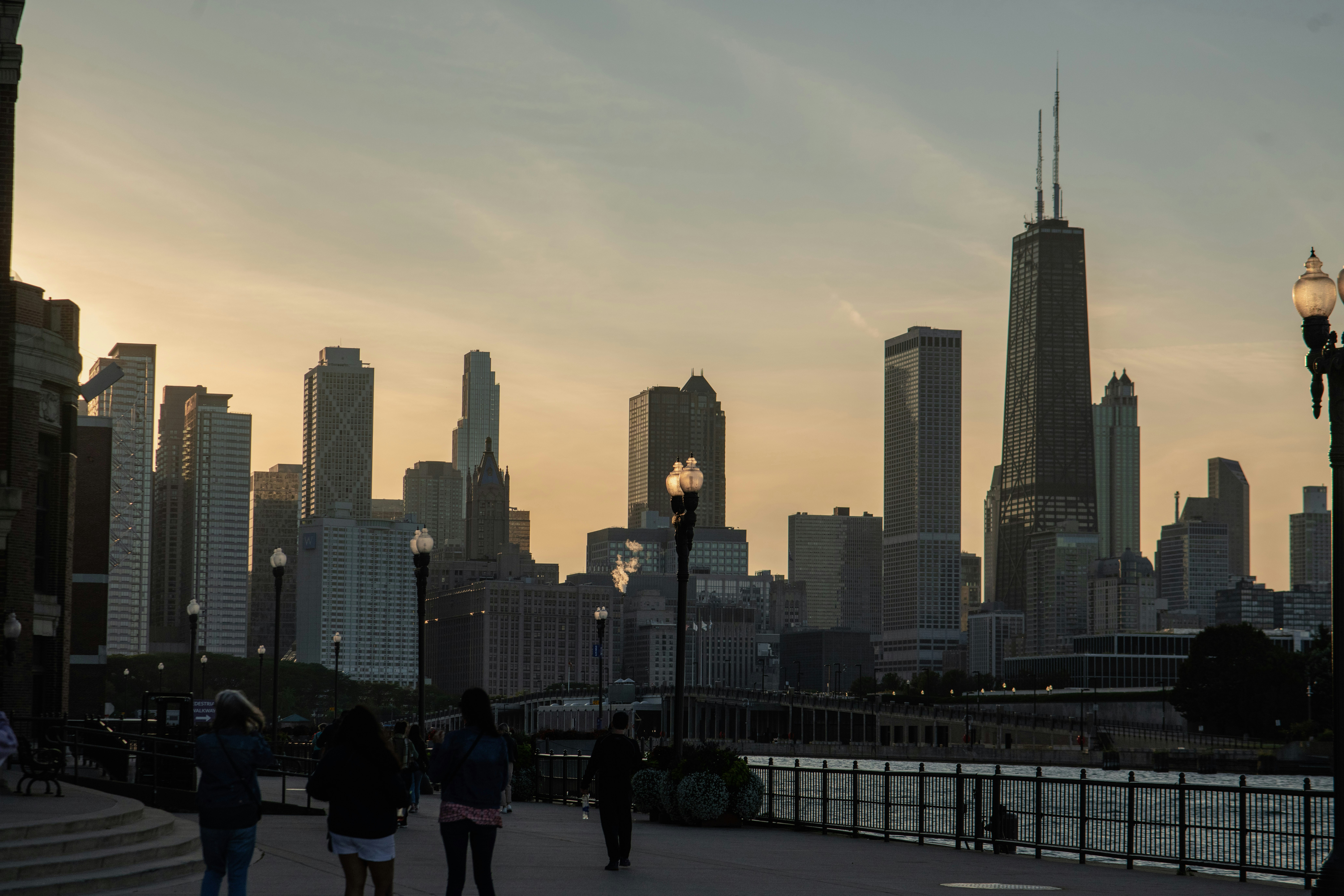 a group of people walking across a bridge next to tall buildings