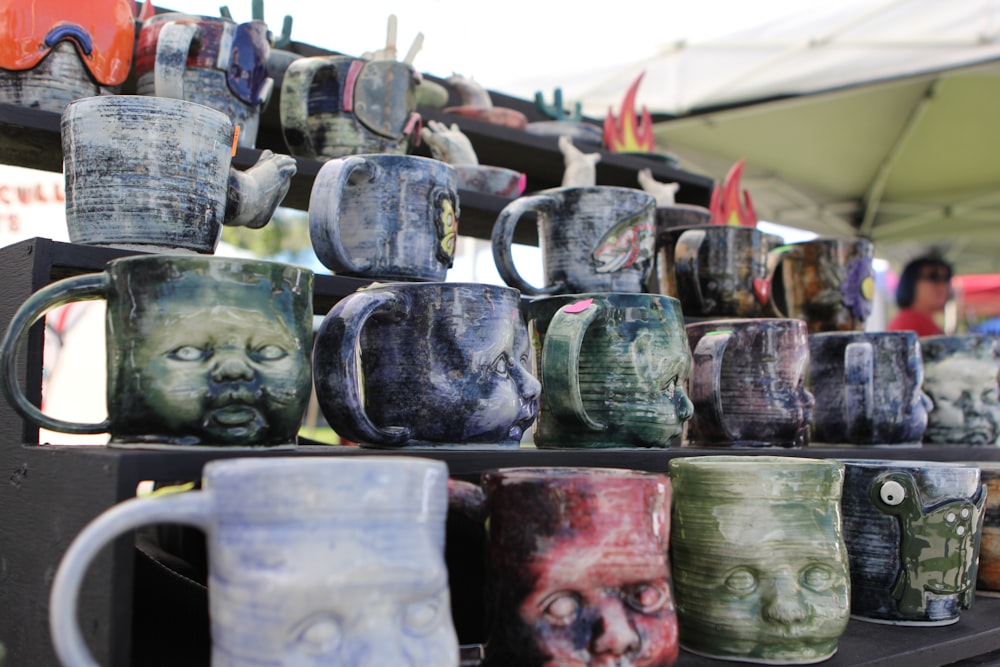 a display of mugs with faces painted on them