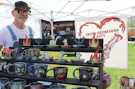Smiling local artisans posing together at one of our outdoor events beside handcrafted pottery.