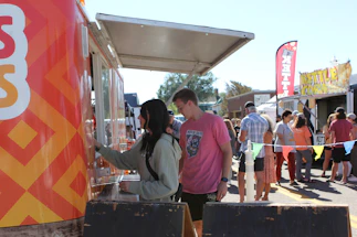 A cozy food truck at a lively Alsatian market, with customers enjoying traditional dishes.
