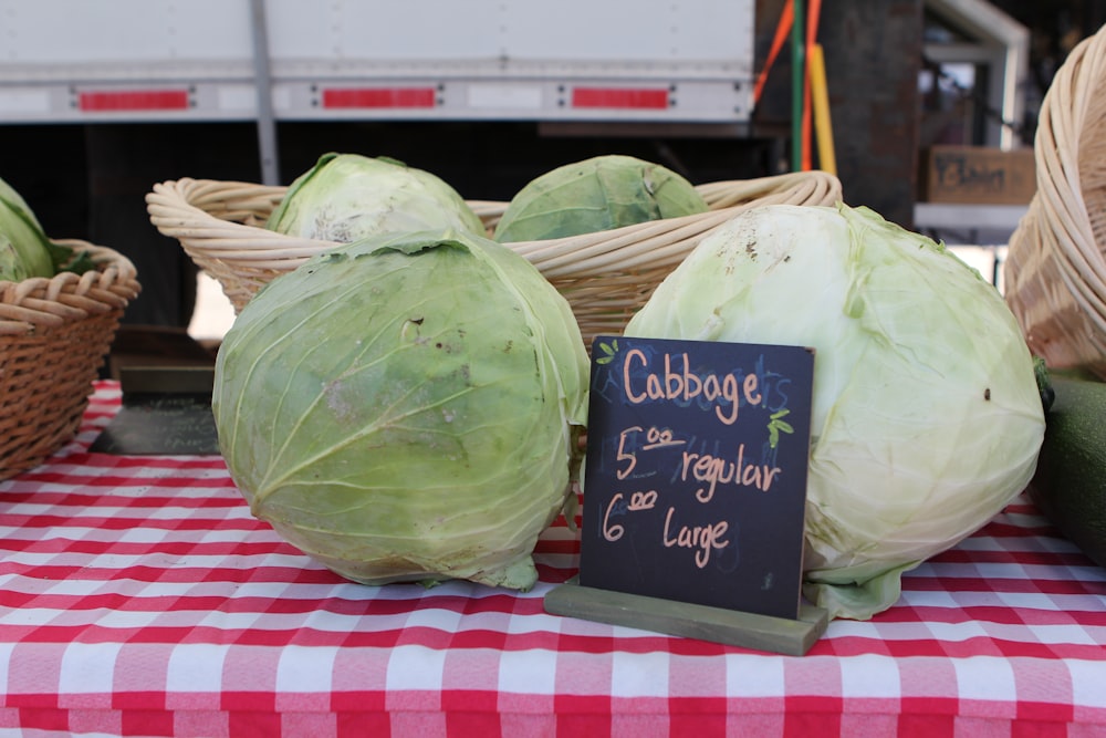 a table topped with cabbage next to baskets of vegetables