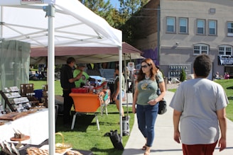 Local businesses showcasing their products at a community fair under colorful tents on a sunny day.