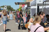Community members gathered around a local market stall during a sunny day in Leinì