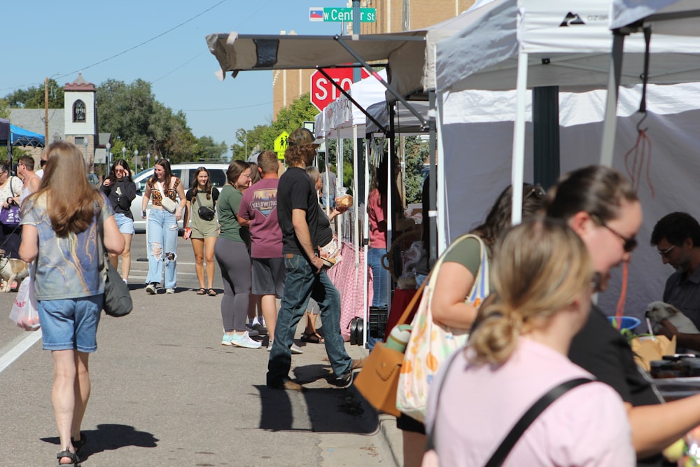 a group of people walking down a street next to tents