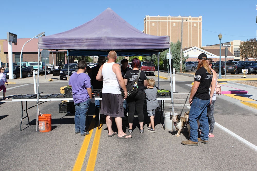 a group of people standing under a purple tent