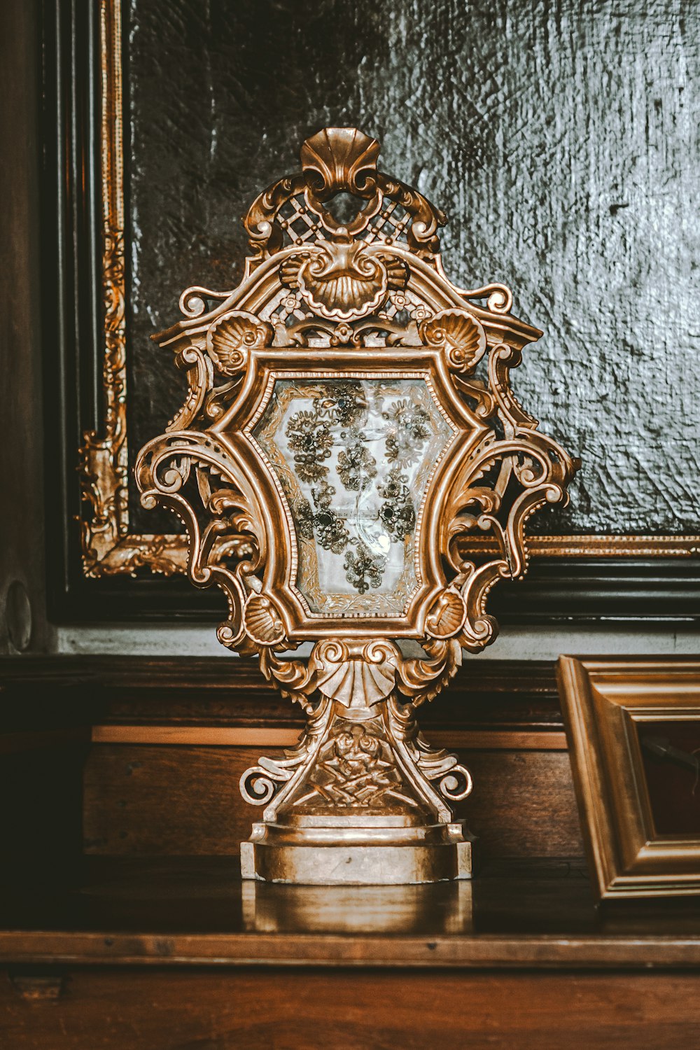 a gold clock sitting on top of a wooden table