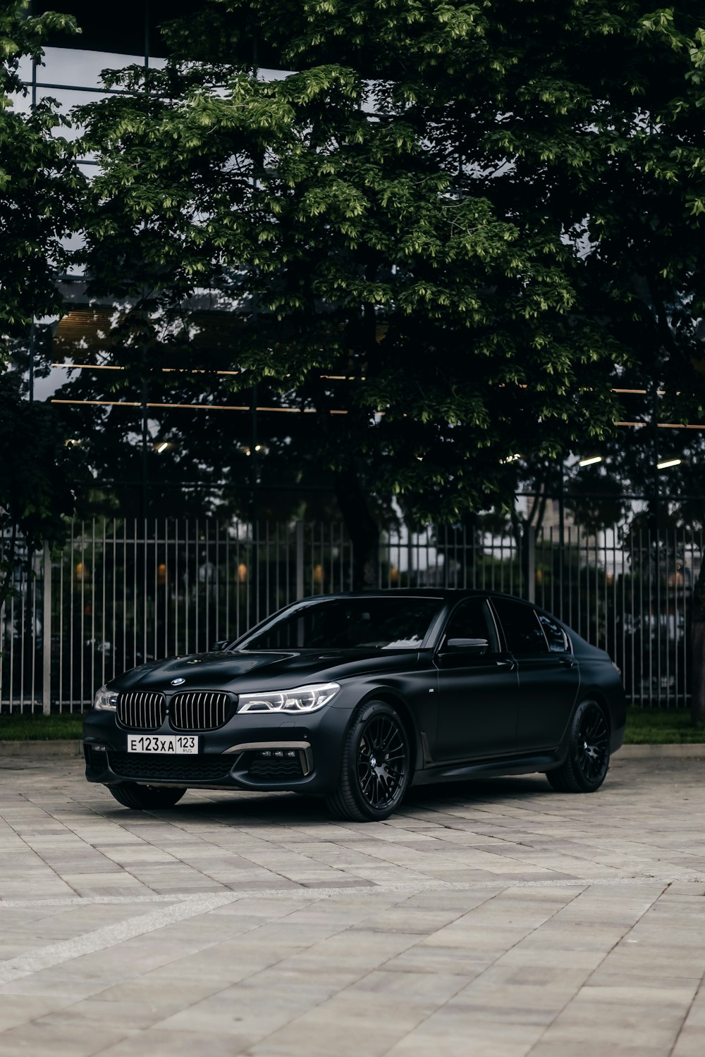 a black car parked in front of a fence