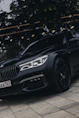 A sleek black luxury sedan parked curbside with city lights reflecting off its polished surface.