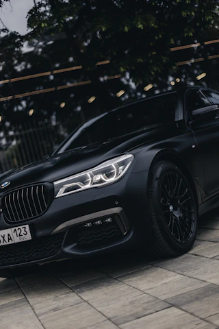 A polished black luxury sedan parked outside an upscale business district at twilight.