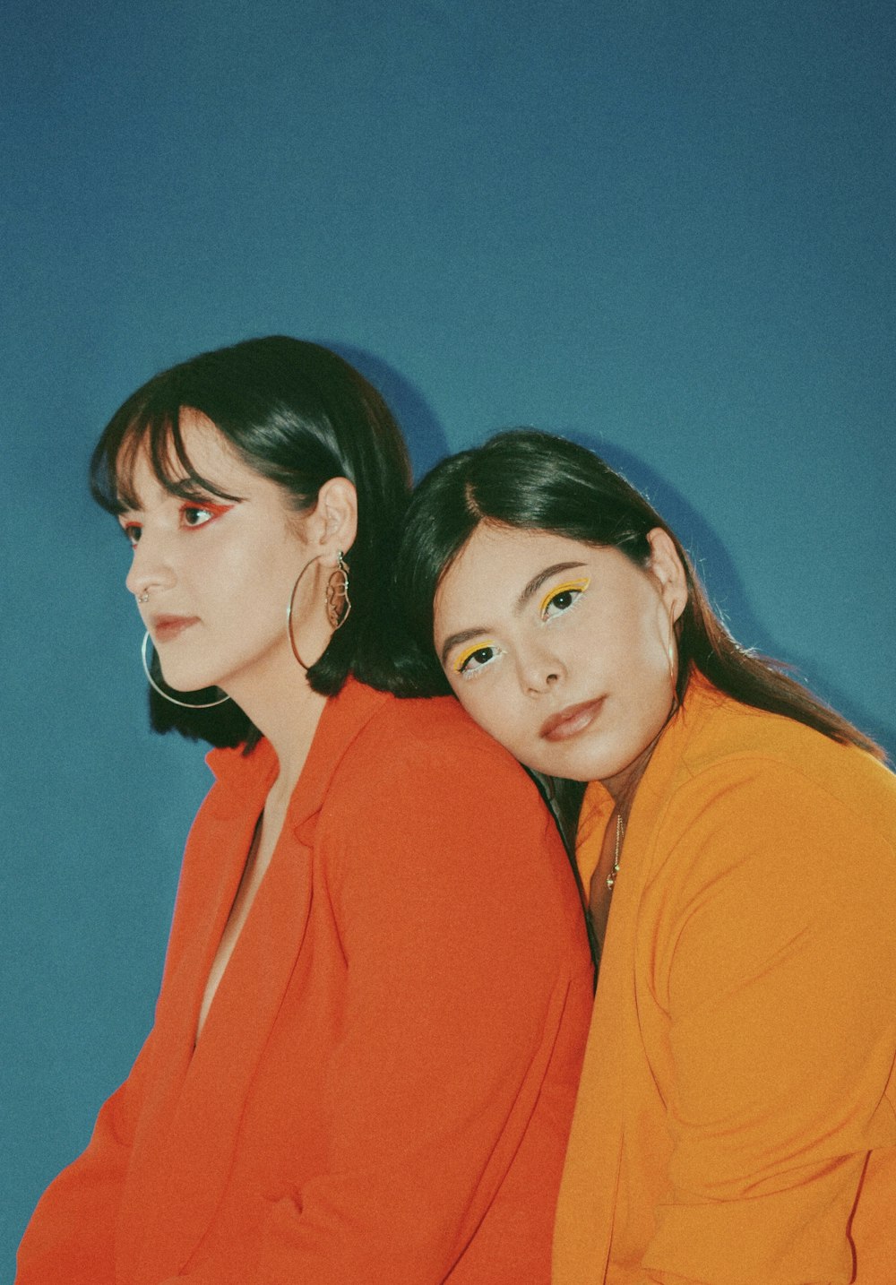 two women sitting next to each other on a blue background